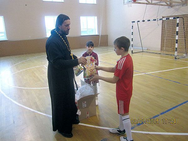 Иерей Николай Клигун вручает подарки юным футболистам